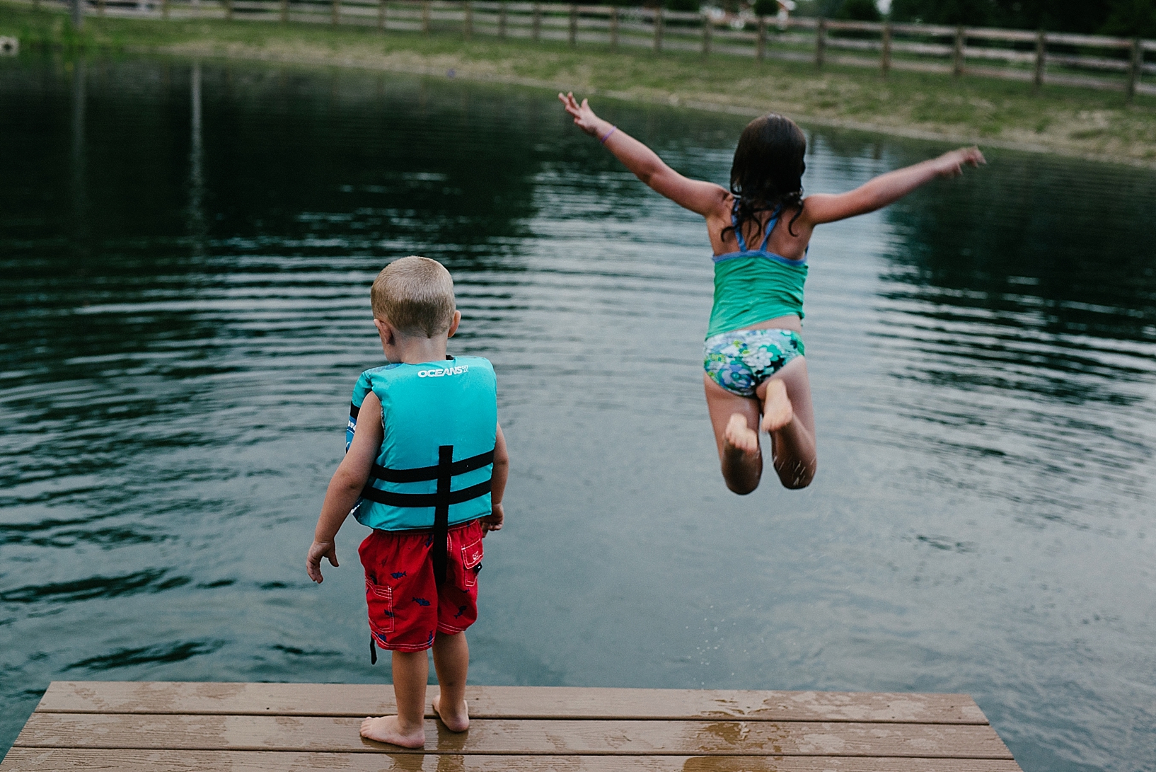 young girl jumping off dock into pond