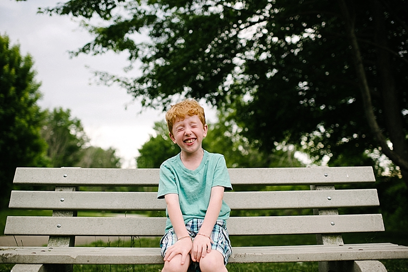 redhead boy sitting on park bench laughing