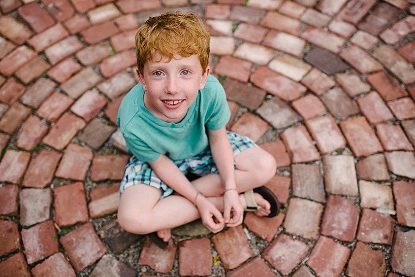 redhead boy sitting on brick path