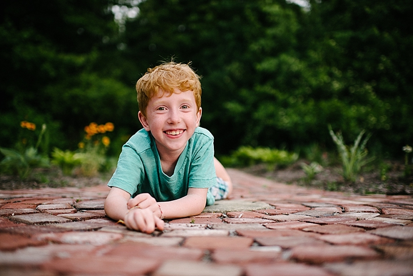 redhead boy laying on brick path