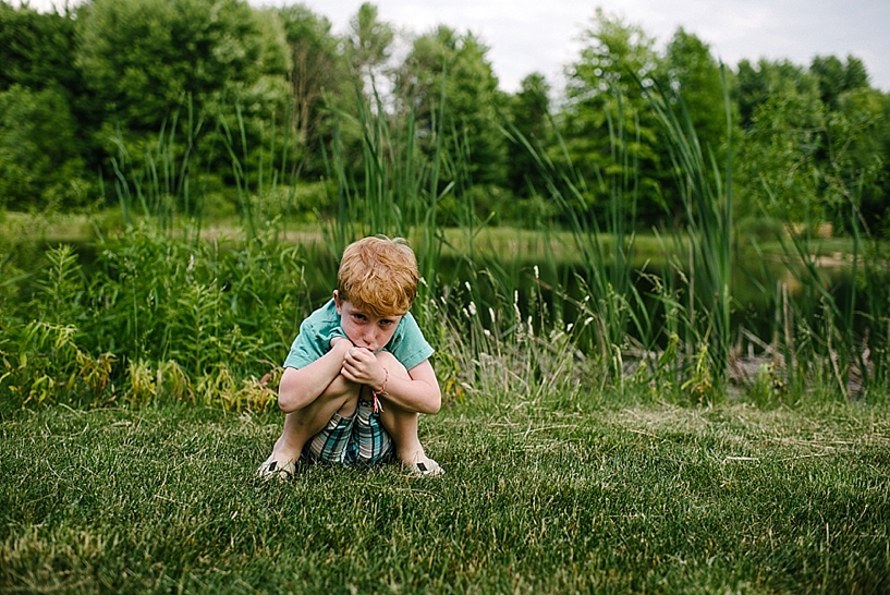 redhead boy sitting by pond