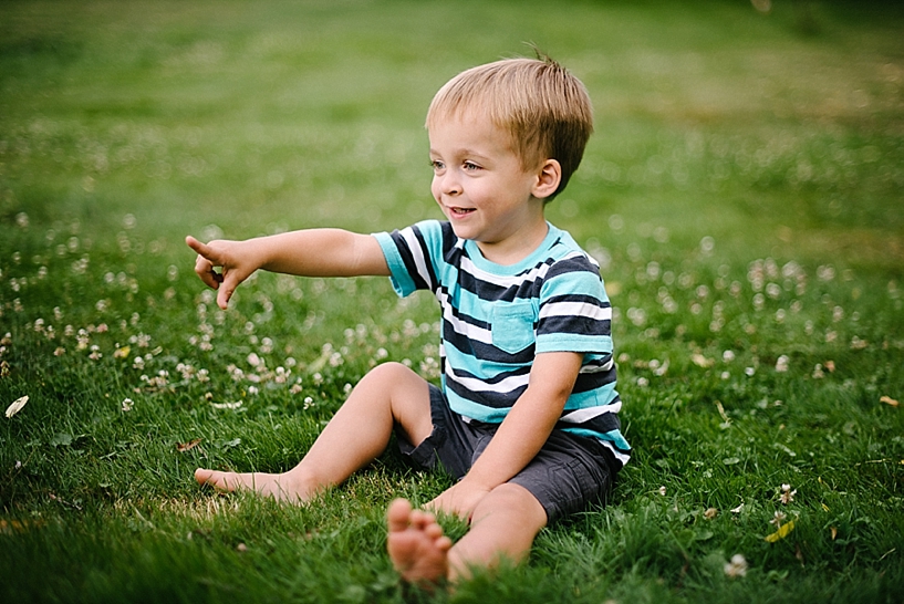 little boy sitting in the grass pointing