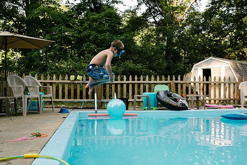 little boy doing a cannon ball into swimming pool