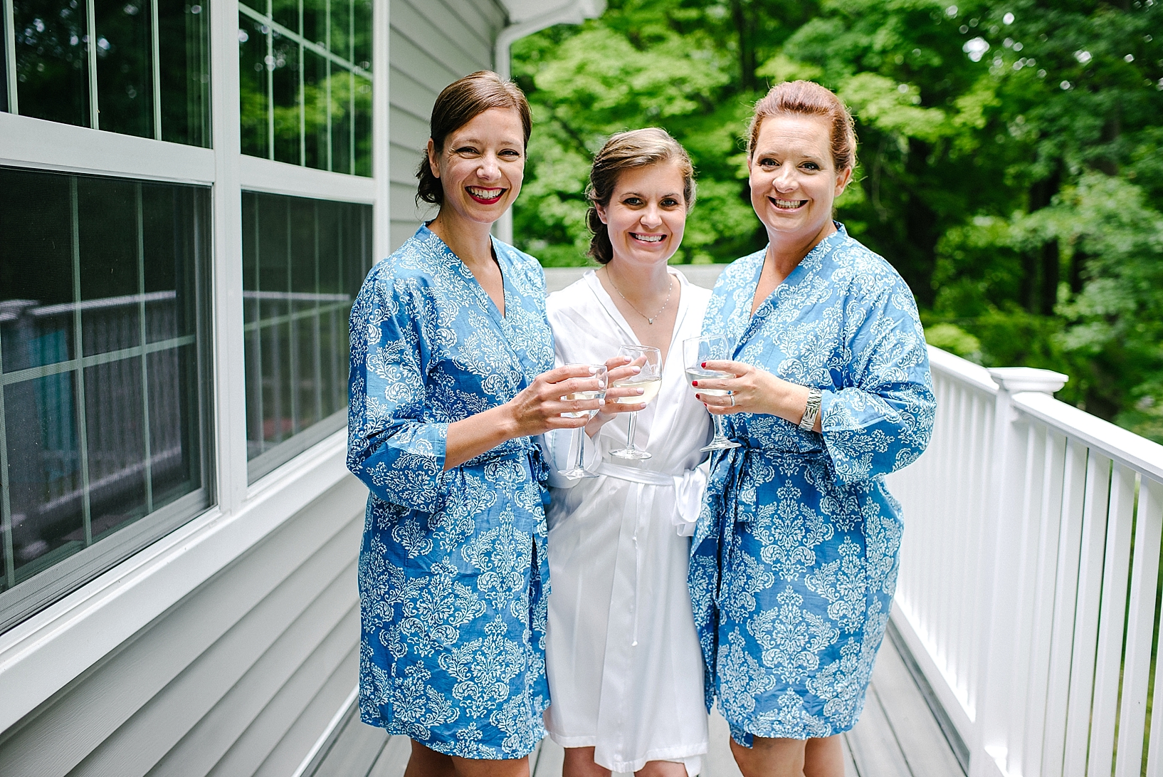 bride with bridesmaids in blue robes toasting champagne