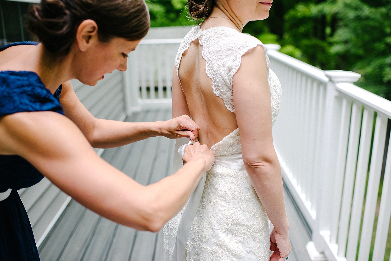 bridesmaid helping bride into her dress