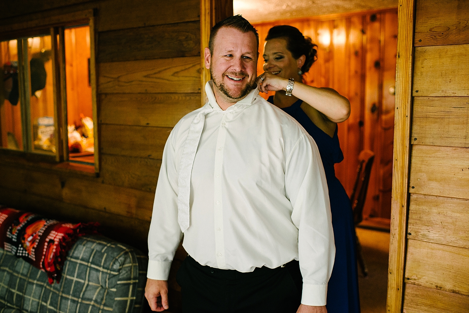 maid of honor helping groom get dressed