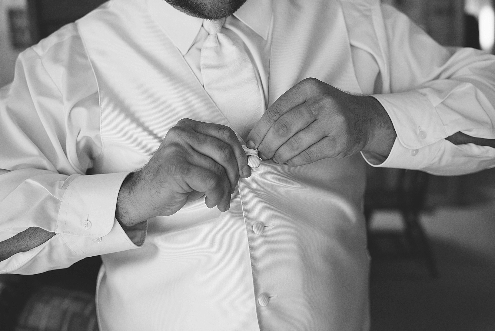 groom buttoning his vest