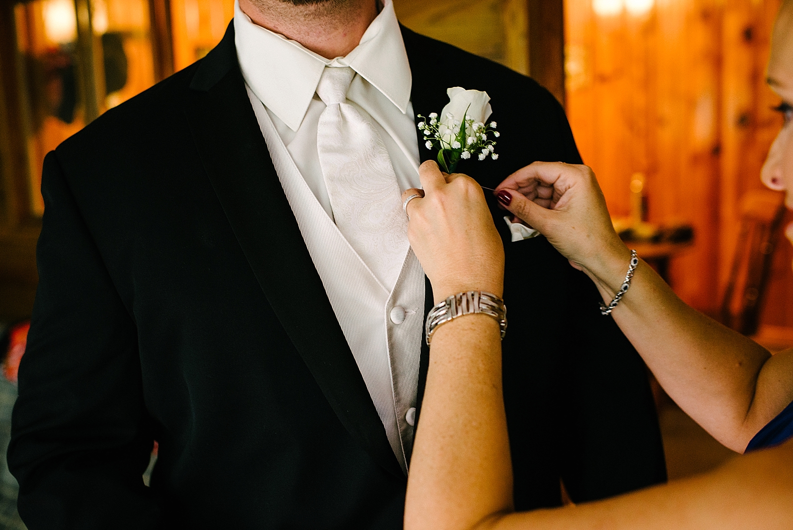 pinning boutonniere on groom