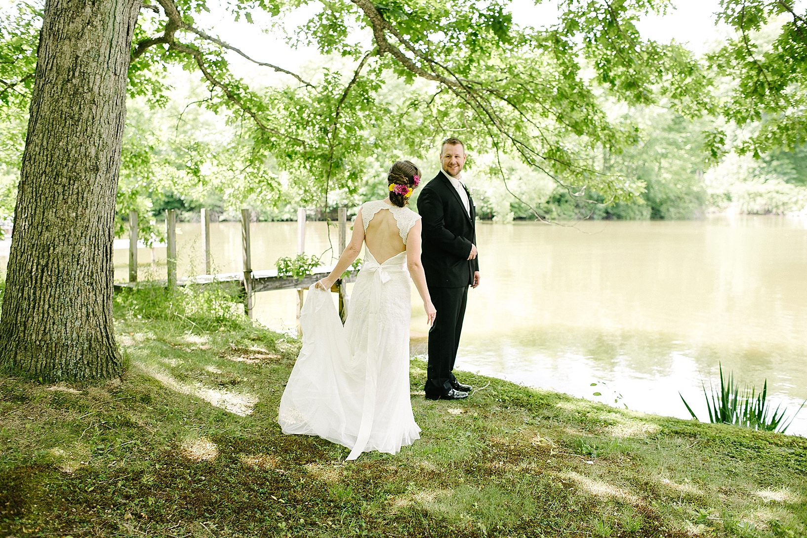 First Look between bride and groom by lake with pier