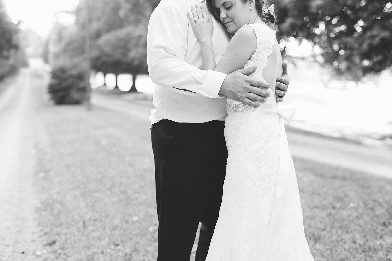 bride and groom standing on dirt country road at sunset