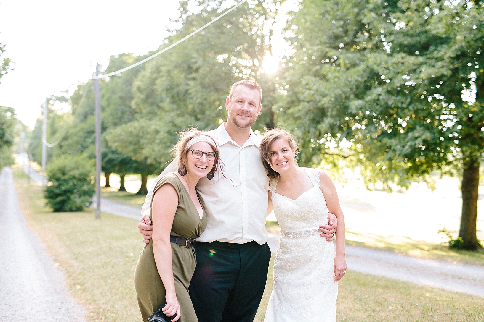bride and groom standing on dirt country road at sunset