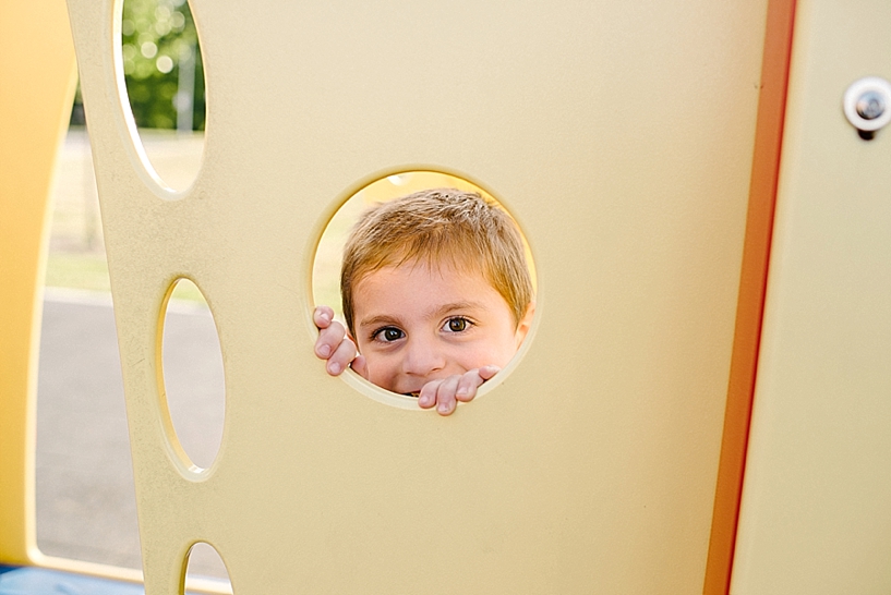 little boy peeking through playground