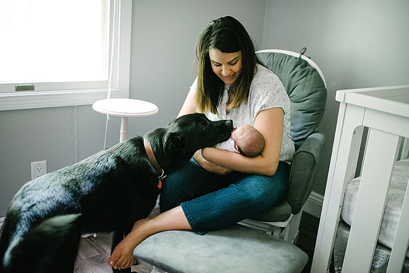 mother rocking newborn with dog nearby