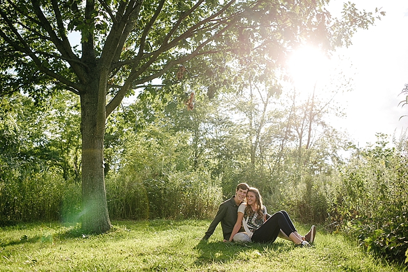 couple sitting by tree with sun shining