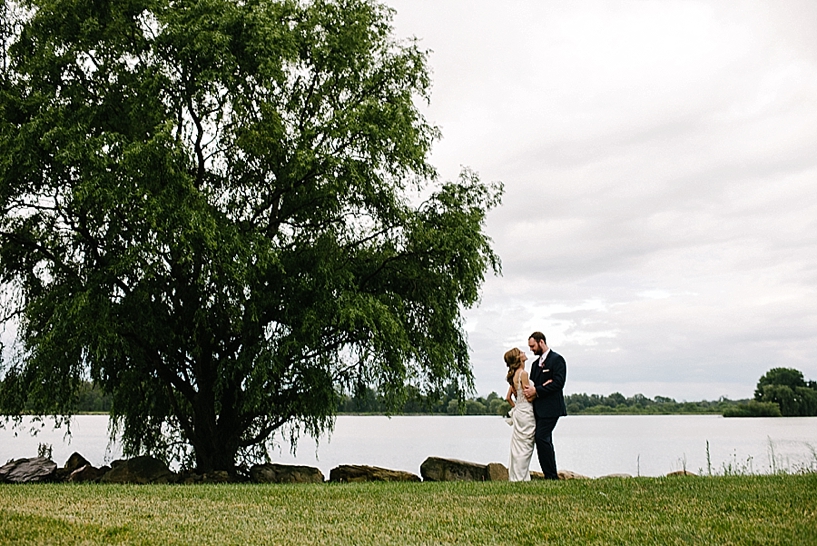 bride and groom standing by lake at Drake's Landing