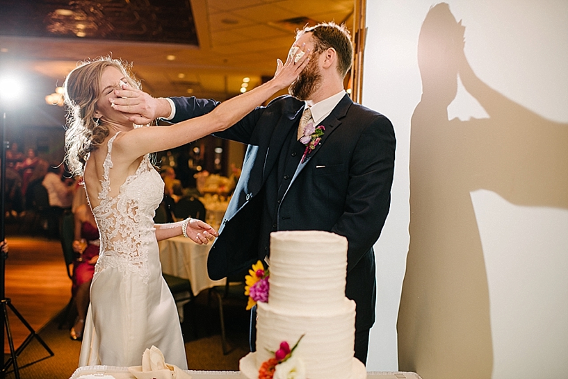 bride and groom smash cake in each other's face