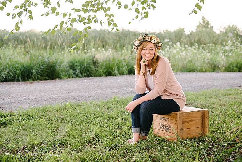 redheaded woman wearing a floral crown sitting on a wooden crate