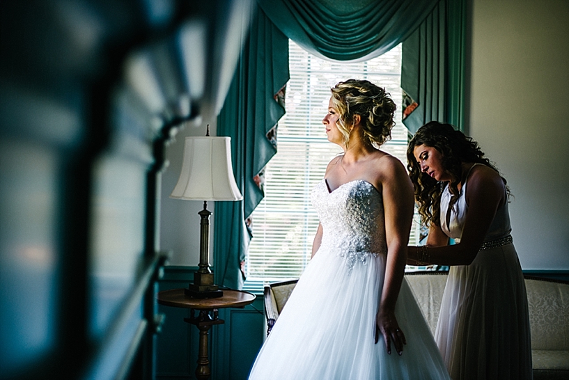 maid of honor helping bride into her gown