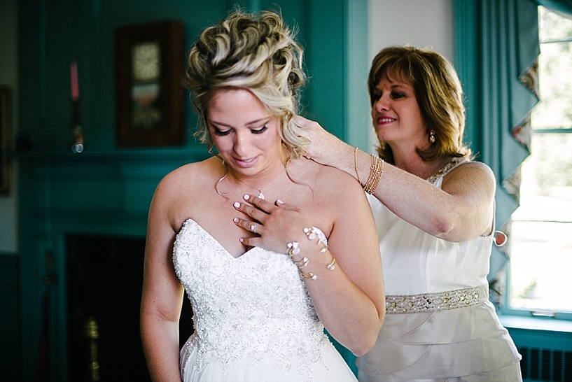 mother putting necklace on bride