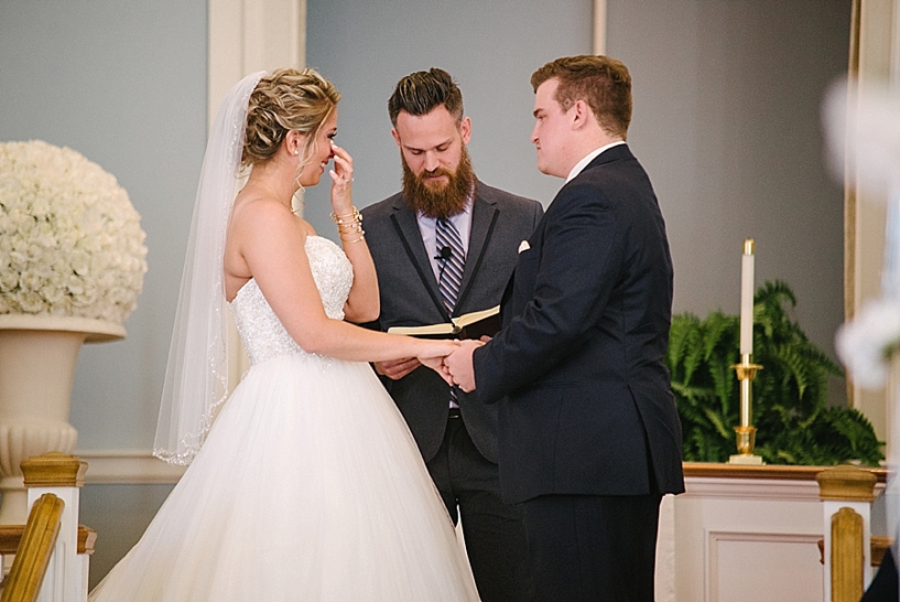 bride wipes away tear while exchanging vows