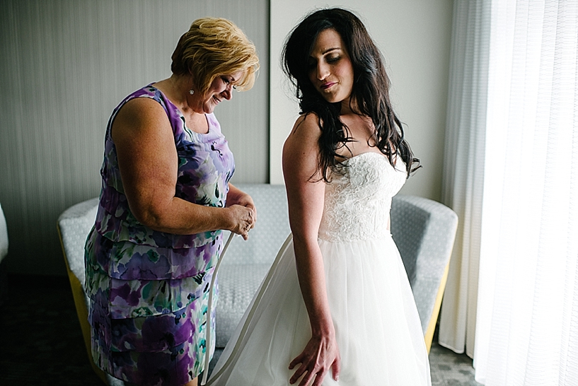 mother helping bride into her wedding gown