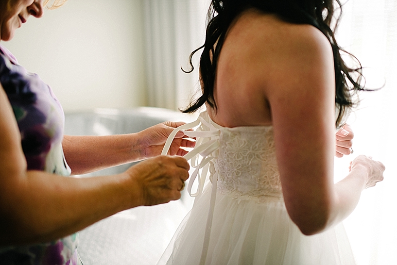 mother lacing bride's wedding gown