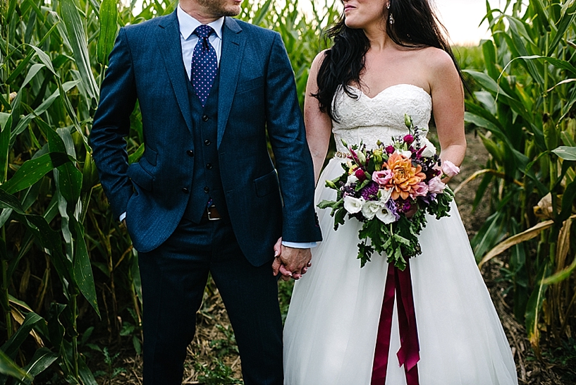 groom in navy suit and bride with colorful bouquet