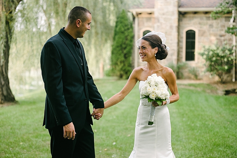 bride and groom holding hands smiling at each other