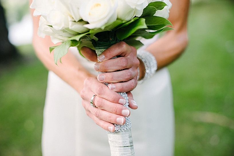 bride's hands holding bouquet of white roses