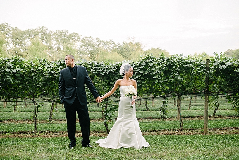 bride and groom holding hands in vineyards at Gervasi