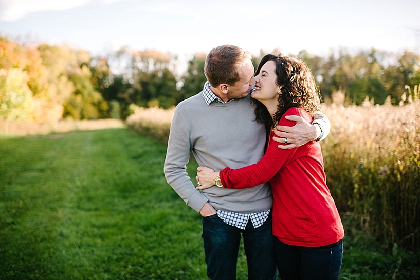 couple standing in front of field hugging each other