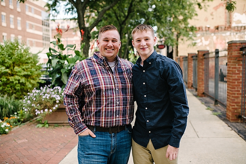 dad in plaid shirt and son in navy and khakis on city sidewalk