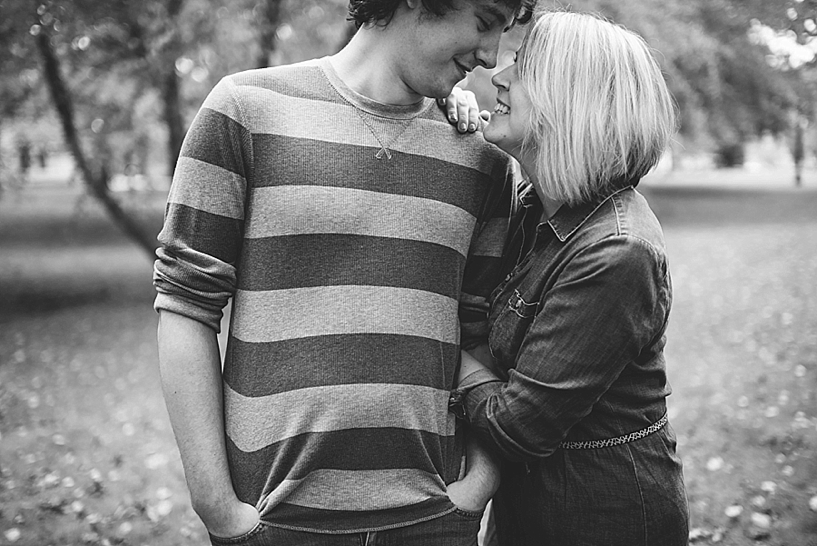 guy in striped sweater and girl in denim dress linking arms and looking at each other