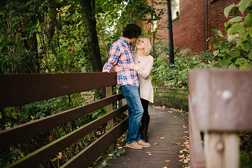 girl in oversized sweater and guy in pink and blue plaid shirt hugging on walking path