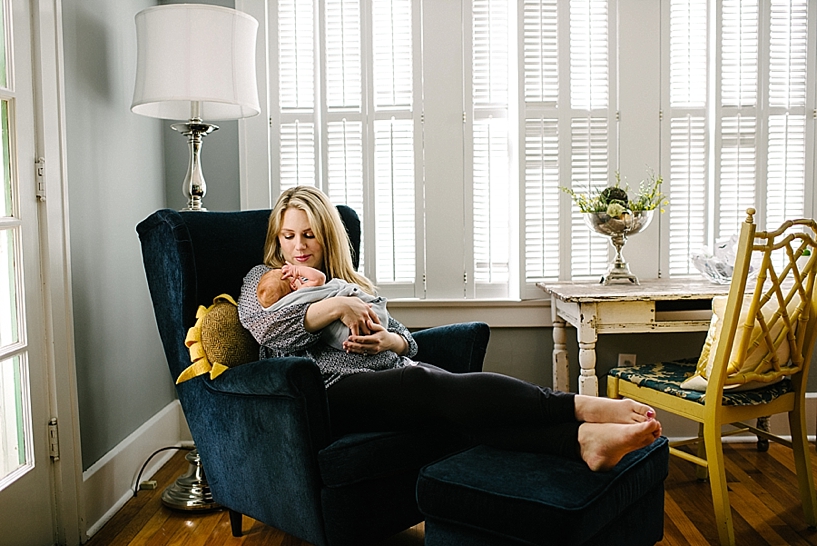 mother sitting in navy chair holding newborn baby