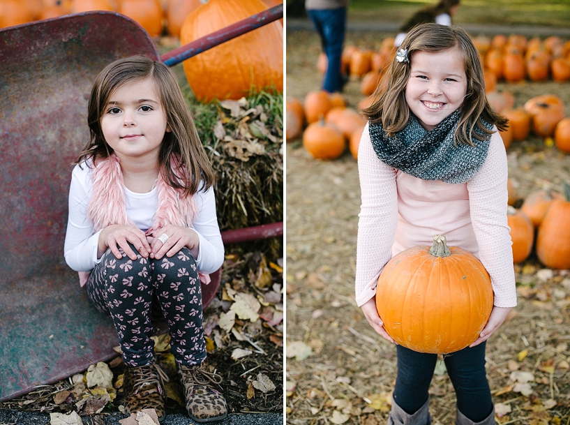 little girl wearing pink shirt and scarf holding a pumpkin and smiling