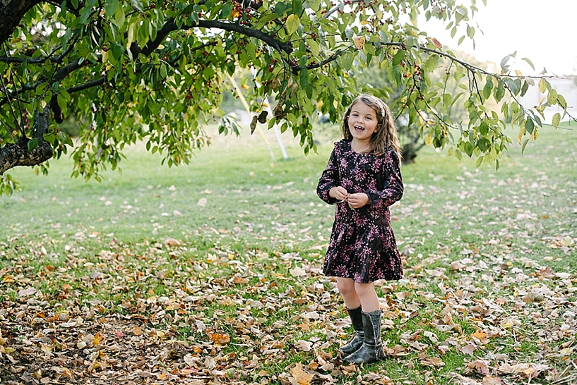 little girl in dress standing by apple tree