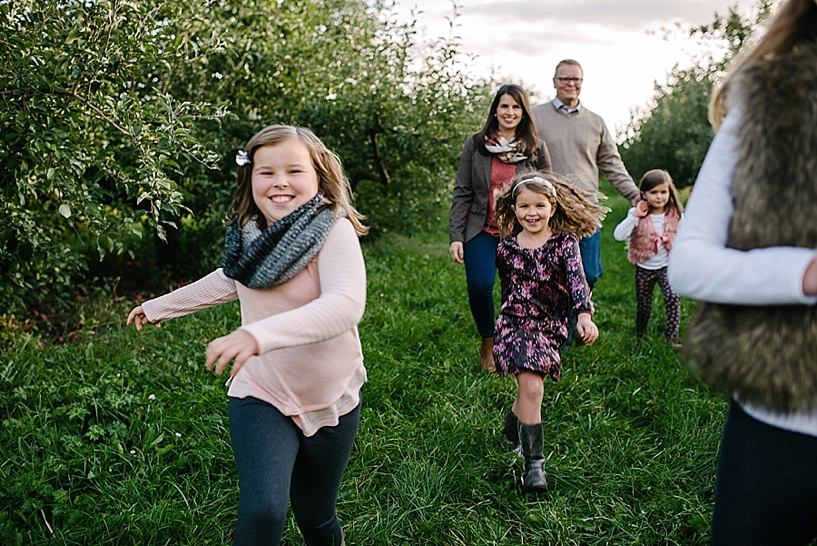 parents and four daughters walking through apple orchard