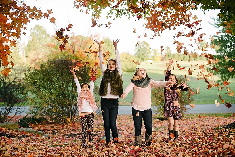 four girls throwing leaves in the air and laughing