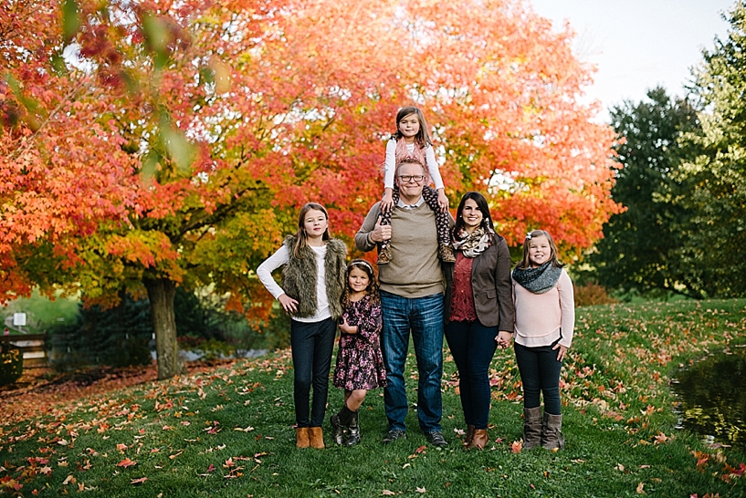 family with four daughters standing by pond with orange tree in the background
