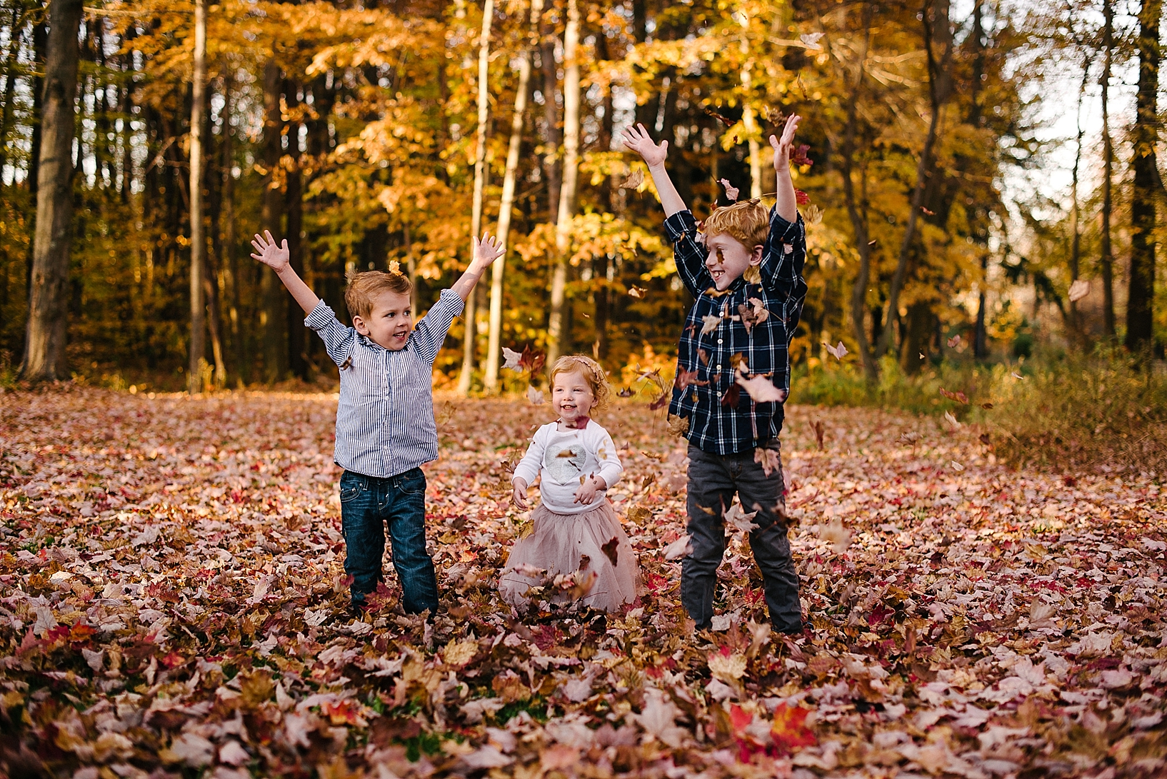 kids throwing leaves up in the air and laughing
