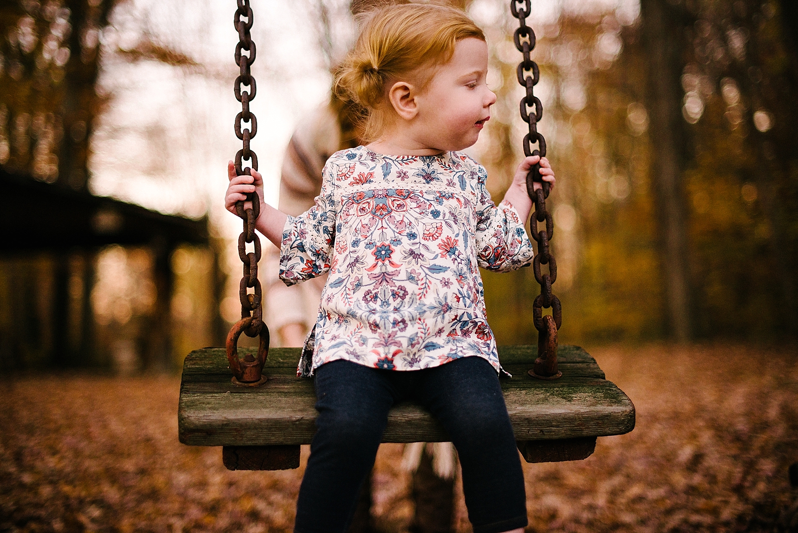 little girl wearing floral print shirt and pigrails swinging in backyard