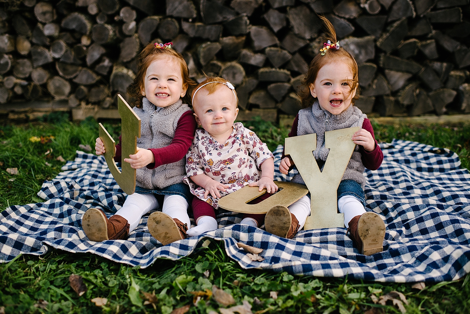 three redhead toddlers sitting on blue plaid blanket holding letters that spell JOY