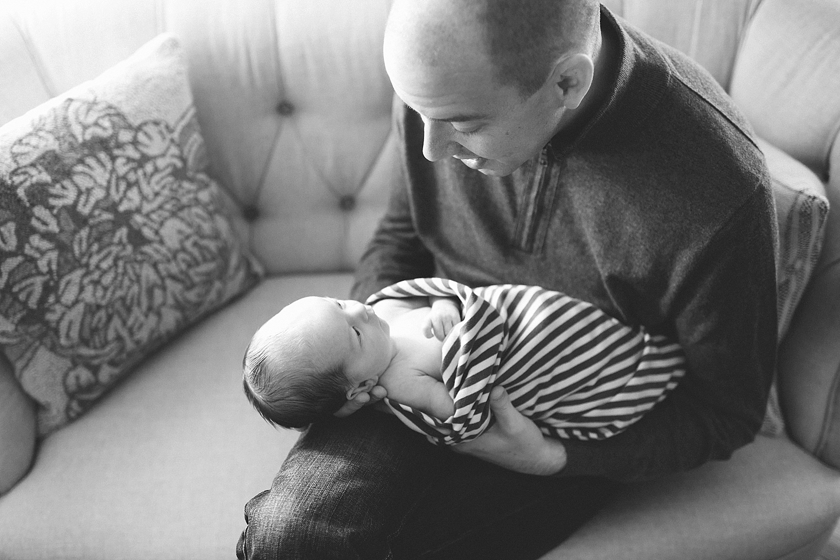dad holding newborn baby wrapped in striped blanket