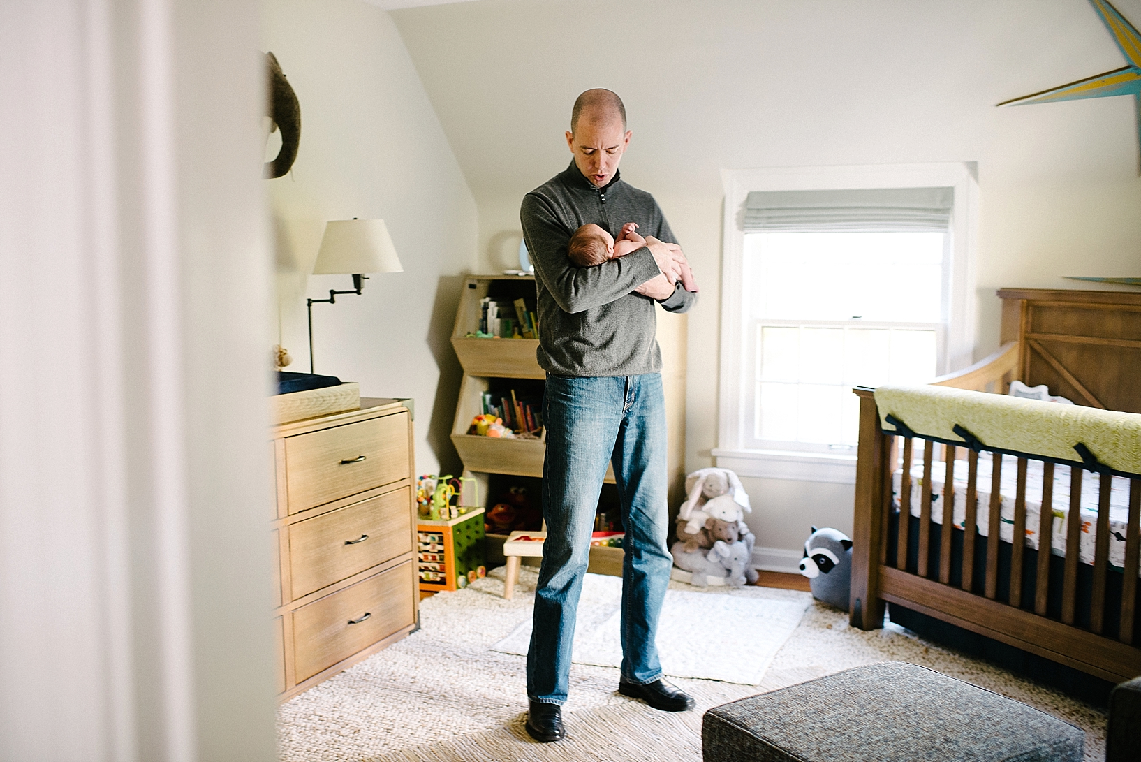 father standing in middle of nursery rocking newborn baby