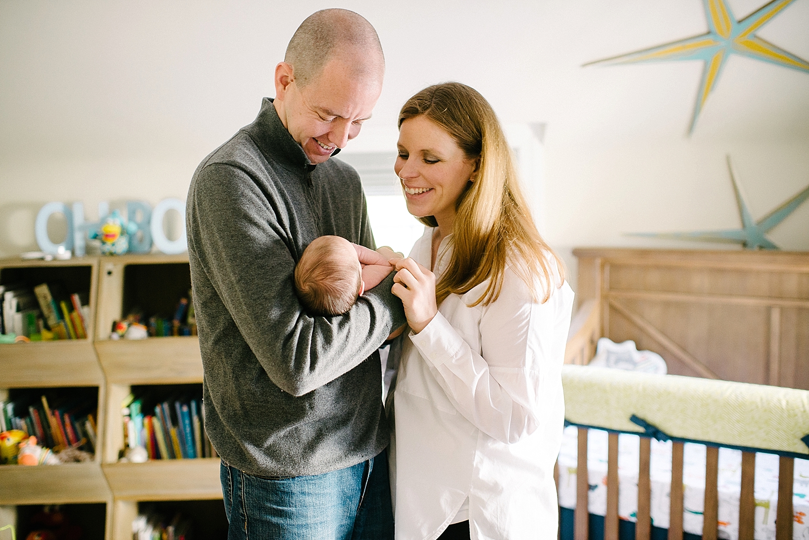 parents standing in middle of nursery holding baby and smiling
