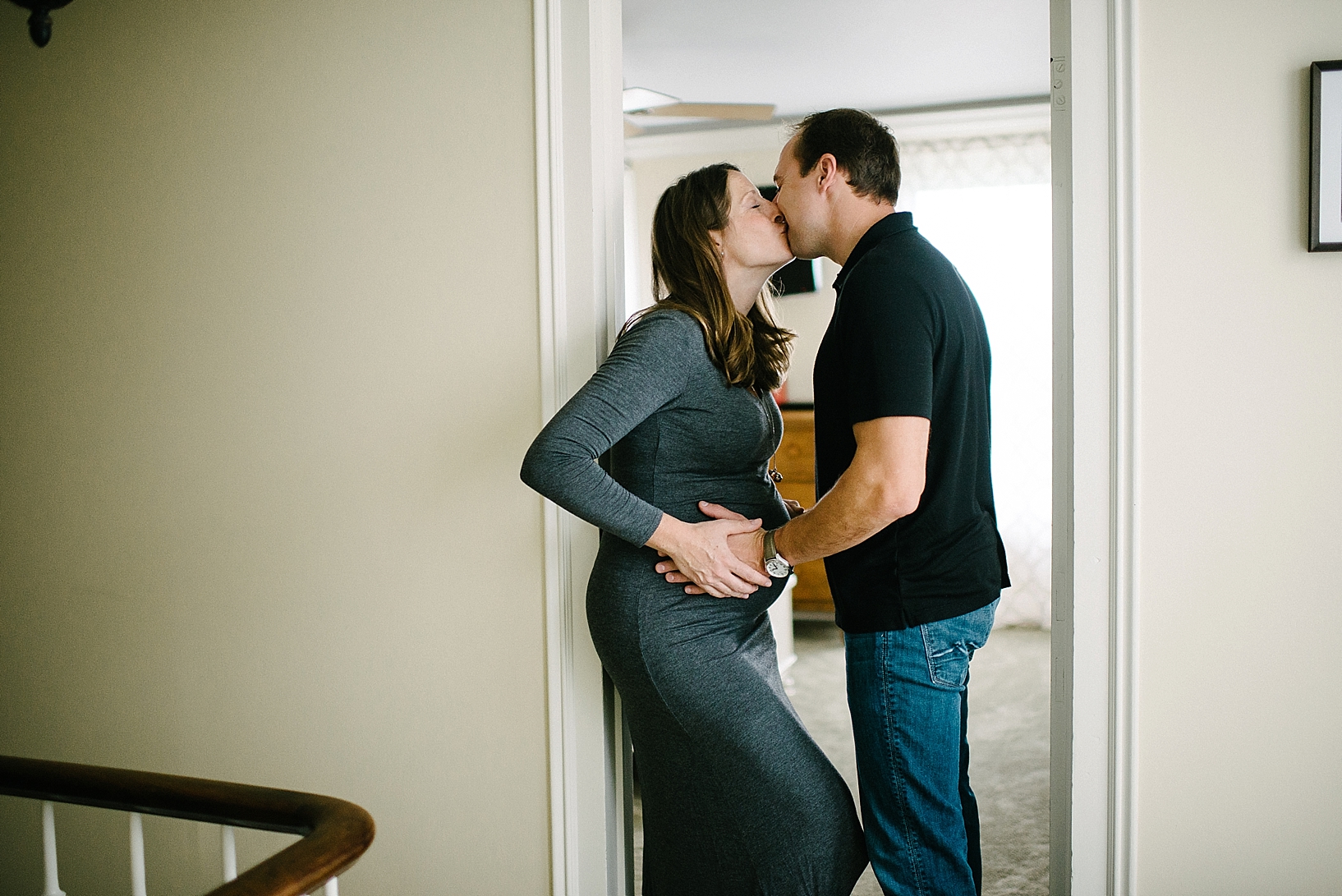 expectant mother and father kissing in doorway