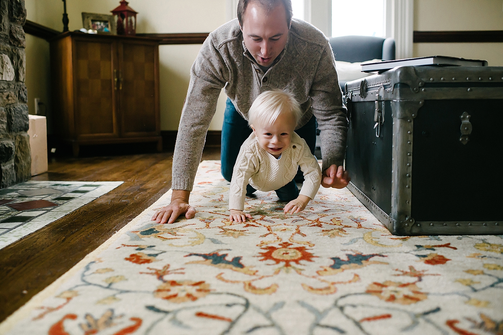 dad and son crawling across living room floor