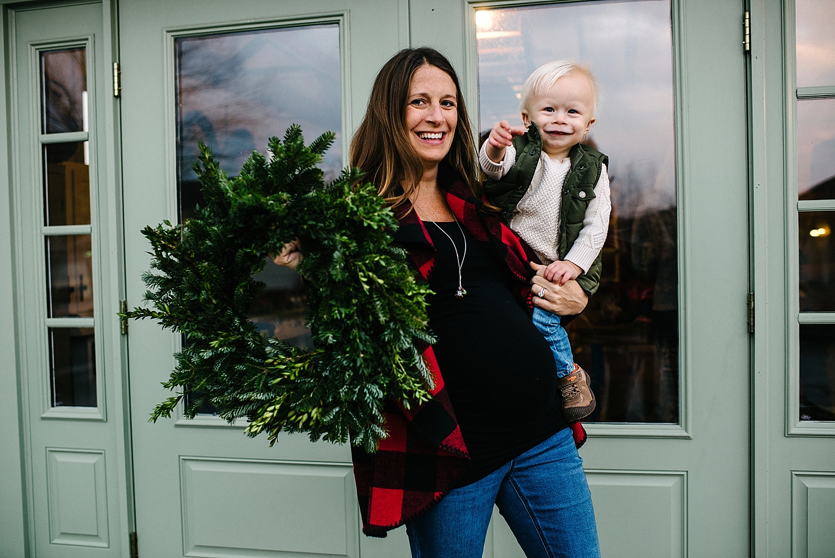 expectant mother holding son and handmade wreath