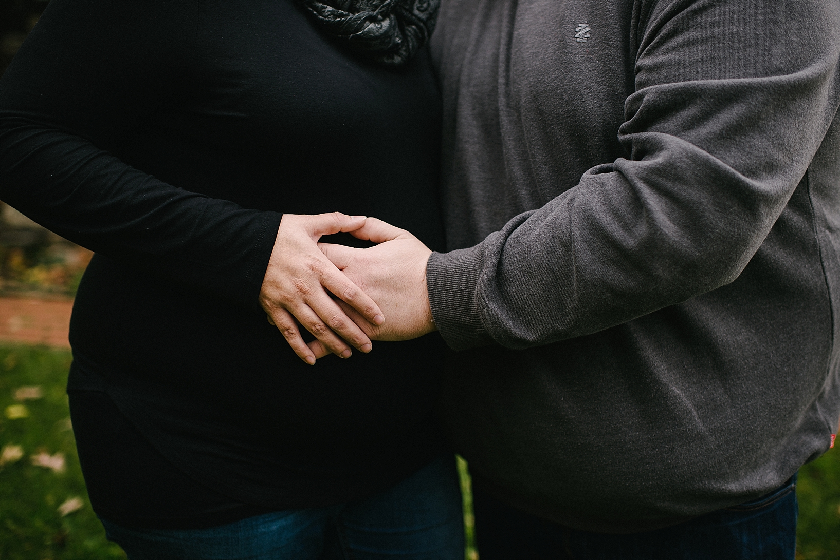 expectant parents hugging with hands on belly